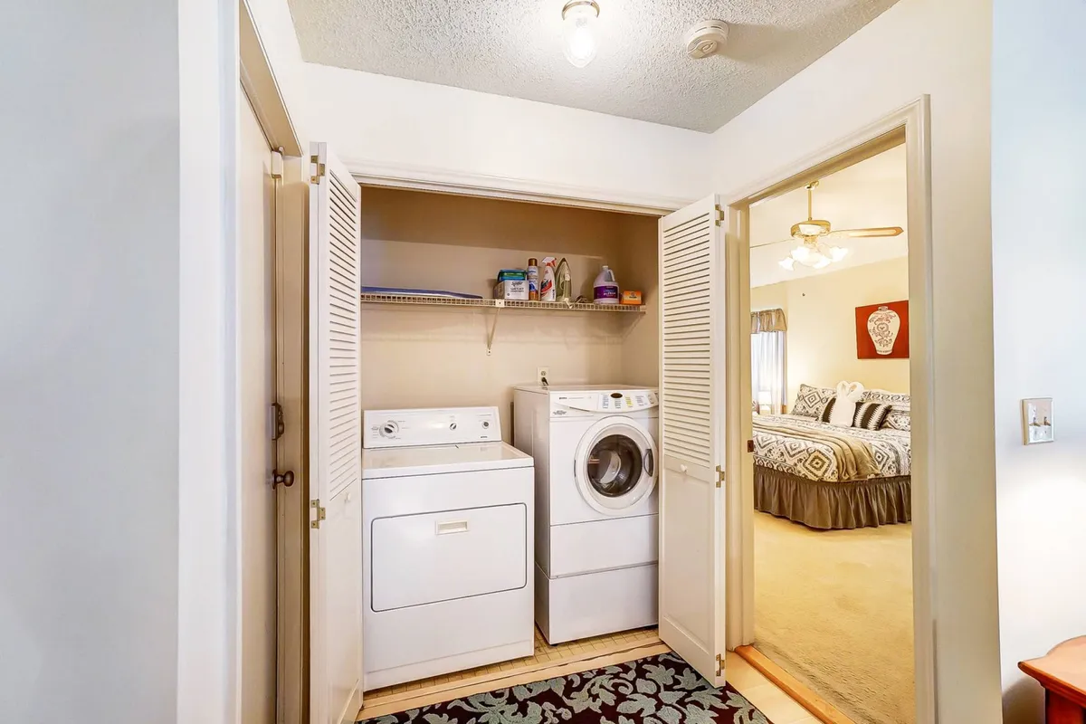 A tidy laundry area equipped with a washer, dryer, and shelves neatly stocked with cleaning supplies. The space appears well-maintained and organized, emphasizing convenience and attention to household upkeep.