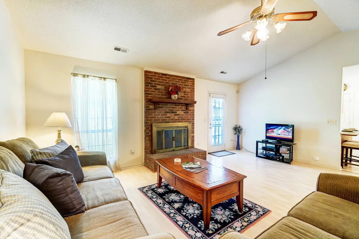 A cozy living area featuring a plush sofa arranged around a coffee table, with a gas fireplace and large flatscreen TV as focal points. The space is styled for relaxation and group activities, with comfortable furnishings and tasteful decor.